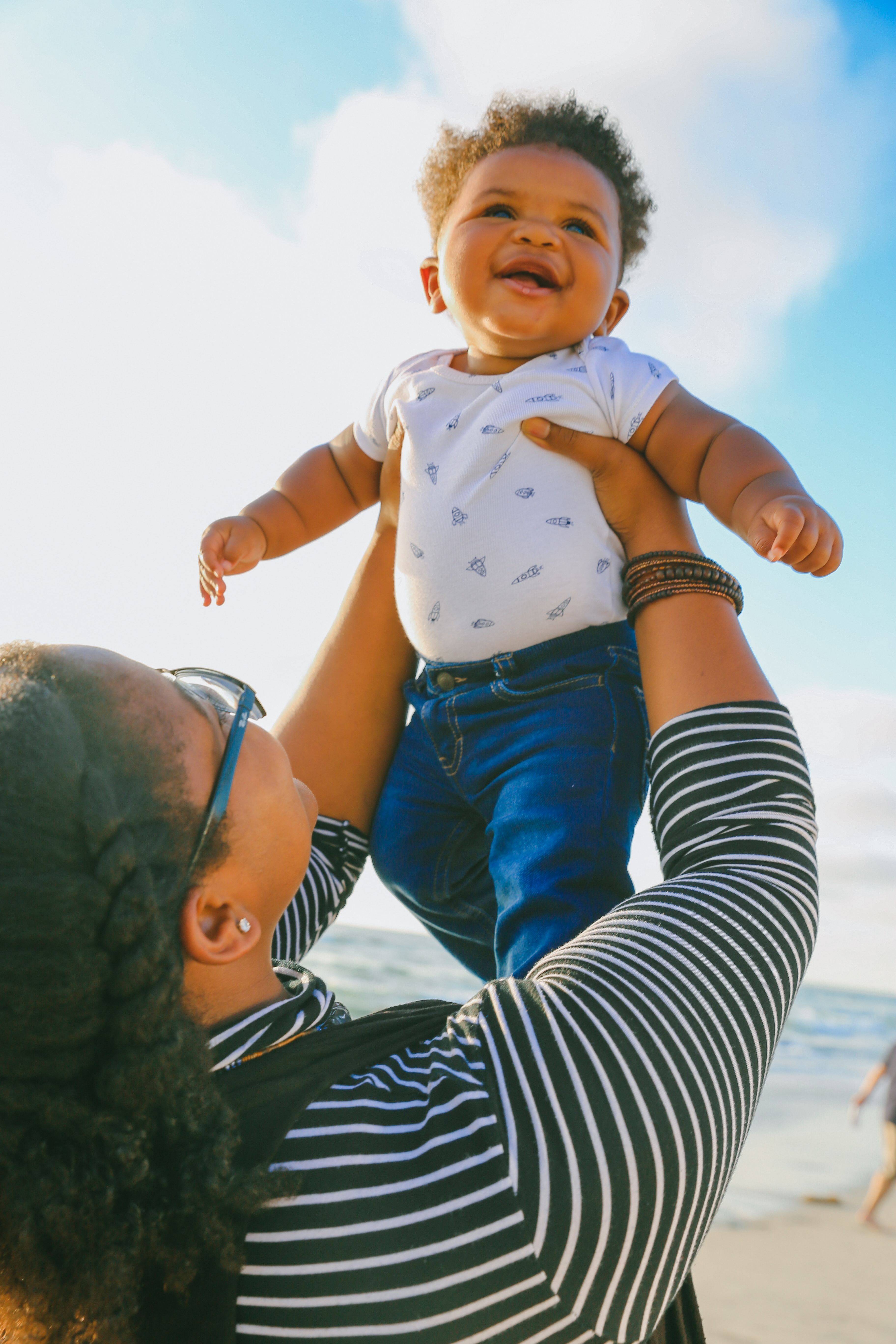 A 4 month old baby is being held up by a young woman.