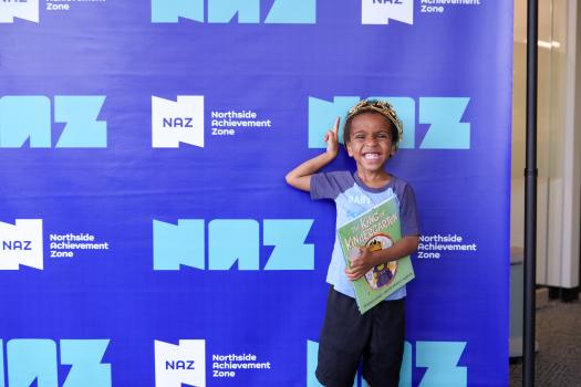 Child wearing a crown and smiling holds a book titled "King of Kindergarten"