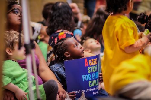 Child looking up, holding a sign