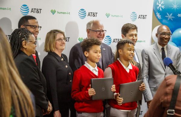 Students stand holding laptops with city leaders.