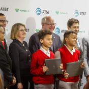 Students stand holding laptops with city leaders.