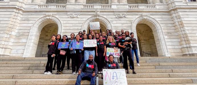 Group of employees stand on the steps of the Minnesota Capitol holding signs