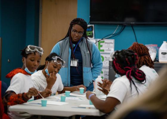 A Medtronic volunteer surrounds herself with four scholars at a STEM event.