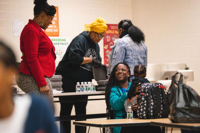 A mother holds her child while talking with a facilitator.