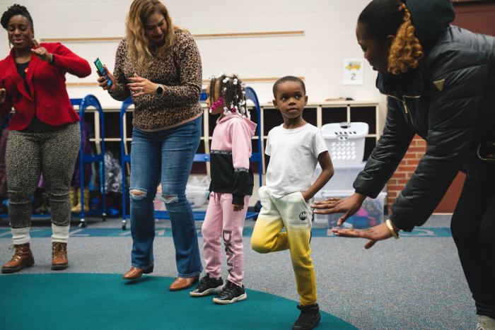_ A child receives instructions from a leader in a circle.