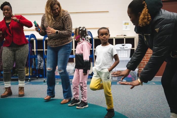 A child receives instructions from a leader in a circle.