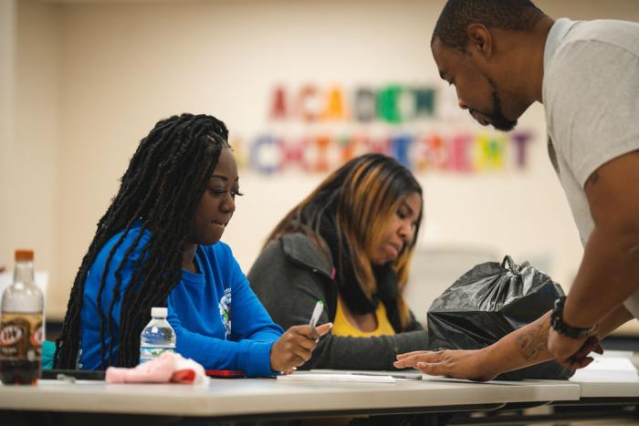 A facilitator and participant look over a page.