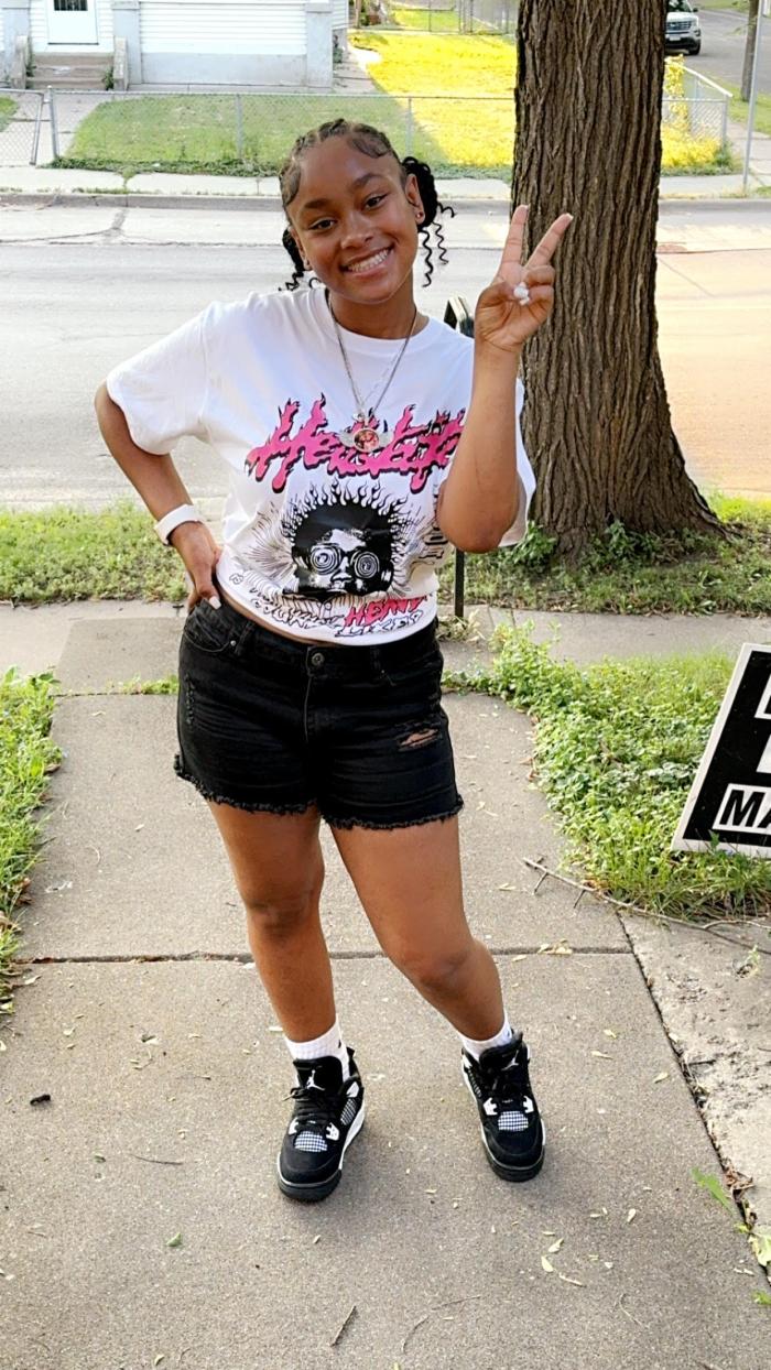 One teen girl stands giving the 'peace' sign