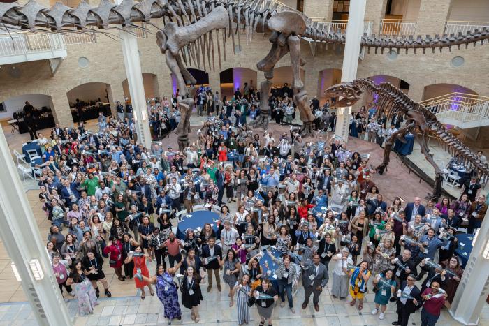 A group of conference goers in a lobby with a dinosaur skeleton