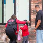A woman hugs a child while her dad stands nearby